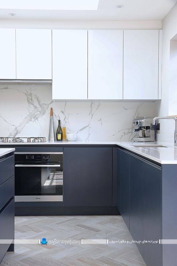 کابینت آبی سرمه ای و سفید آشپزخانه با طراحی مدرن شیک بدون دستگیره. مدب جدید دیوارپوش بین کابینتی طرح سنگی مرمری.