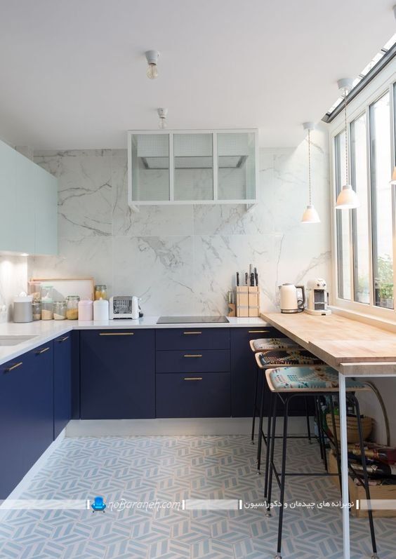 طراحی دکوراسیون آشپزخانه با سرمه ای و سفید. کابینت آبی رنگ کاربنی شیک مدرن با رنگ بندی سفید آبی با دستگیره طلایی رنگ. دیوارپوش سنگی مرمری آشپزخانه برای دیوار بین کابینتی.